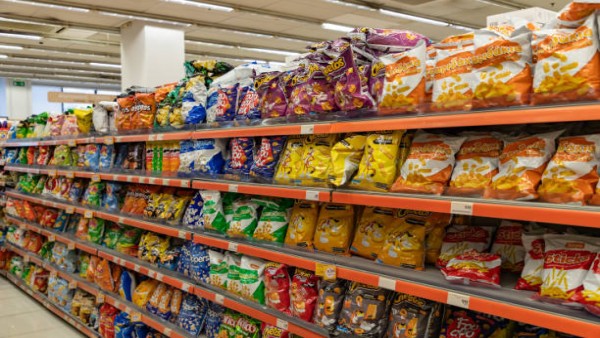 Deretan camilan kemasan seperti keripik dan snack instan terpajang di rak sebuah toko.