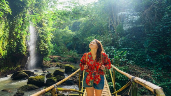 Ilustrasi seseorang menikmati perjalanan sambil berjalan santai di destinasi wisata, melambangkan manfaat traveling bagi kesehatan otak.