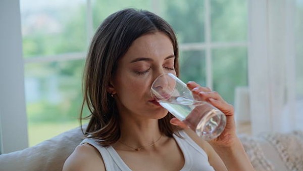 Seorang wanita dewasa menikmati segelas air putih sebagai bagian dari pola hidup sehat.