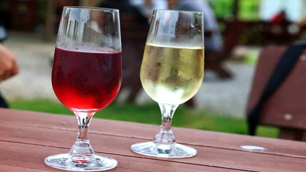 Dua gelas red wine dan white wine yang diminum saat cuaca cerah, menggambarkan perbandingan kedua jenis wine dalam gaya hidup modern.