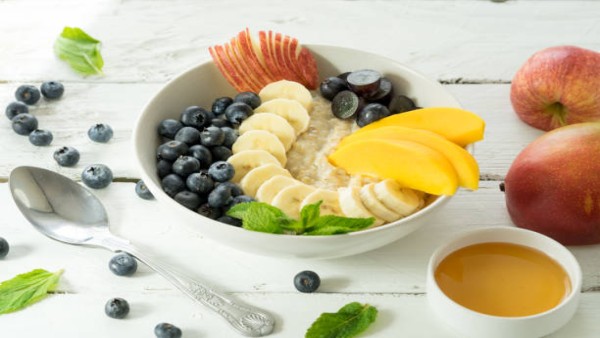 Ilustrasi mangkuk sarapan berisi oatmeal dan buah segar yang mencerminkan menu pagi sederhana namun bernutrisi.