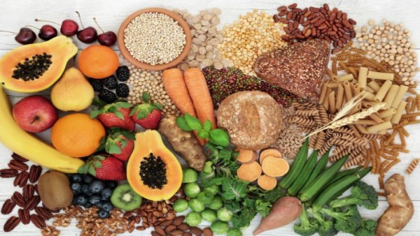 Ilustrasi aneka makanan tinggi serat seperti biji-bijian utuh, kacang-kacangan, sayur, dan buah yang baik untuk pencernaan jika dikonsumsi seimbang.