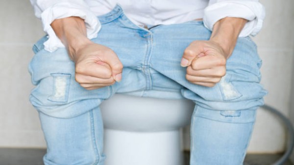 Ilustrasi seseorang mengalami sembelit saat duduk di toilet.