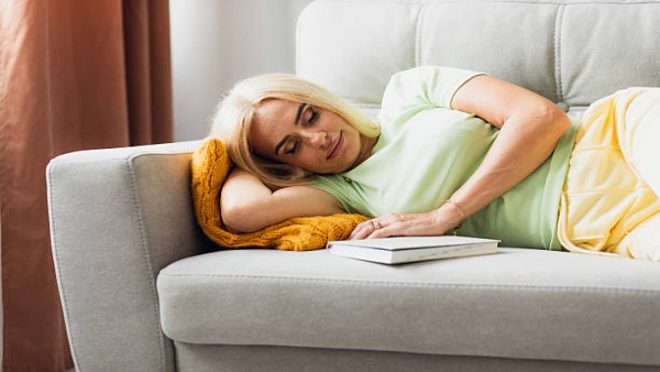 Ilustrasi lansia sedang tidur siang di sofa pada pagi hari.