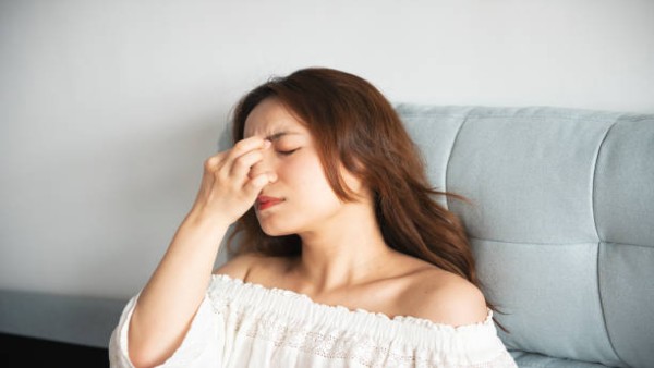 Ilustrasi wanita mengalami nyeri di area hidung dan wajah akibat gejala infeksi sinus.