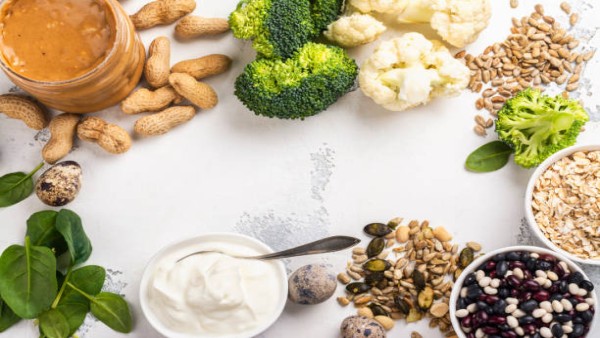 Ilustrasi aneka camilan tinggi protein seperti Greek yogurt, telur rebus, selai kacang, dan roasted edamame yang cocok untuk gaya hidup sehat modern.