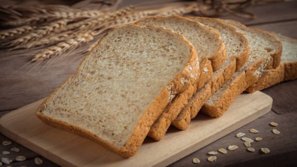 Ilustrasi potongan roti gandum utuh yang kaya serat dan baik untuk menjaga kestabilan gula darah.