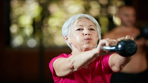 Seorang lansia melakukan latihan angkat beban menggunakan kettlebell sebagai bagian dari rutinitas olahraga untuk menjaga kekuatan tubuh dan kesehatan di usia lanjut.