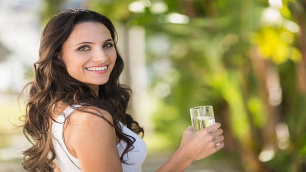 Seorang wanita minum segelas air putih sebelum makan, salah satu kebiasaan sederhana yang disebut dapat membantu menurunkan berat badan tanpa olahraga.