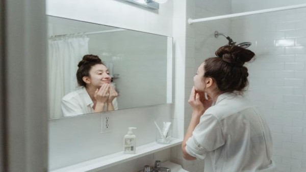 Ilustrasi seseorang merawat kulit wajah menggunakan skincare ringan dan sunscreen saat cuaca panas untuk menjaga kesehatan kulit serta membuat makeup lebih tahan lama.