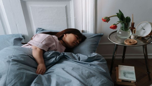 Ilustrasi seorang perempuan tidur nyenyak setelah menerapkan kebiasaan sleep hygiene untuk meningkatkan kualitas istirahat di malam hari.